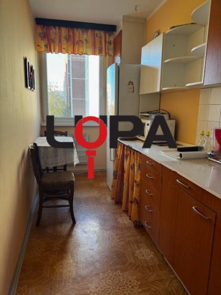 A kitchen in a 3-room apartment with a wooden decor floor and furniture in warm colors.