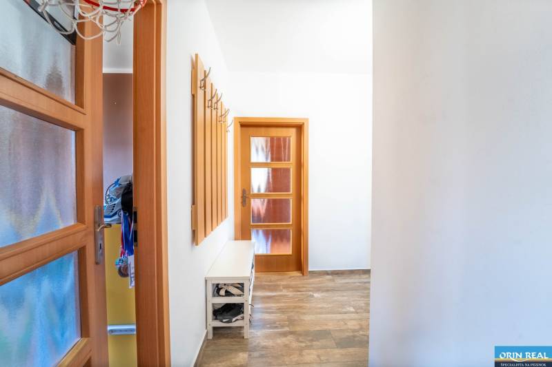 A hallway with a coat rack, a shoe cabinet, and a floor with a wooden decor in a 3-room apartment.