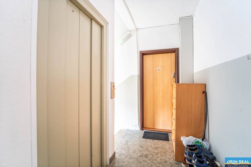 Interior space with an elevator, entrance door, shoe cabinet in a 3-room apartment.