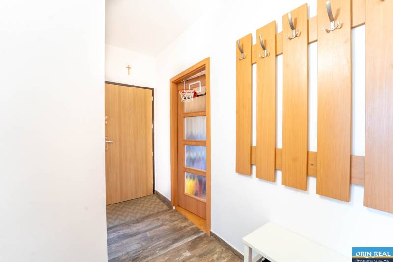 A hallway with coat racks, doors, and a floor with a wooden decor in a 3-room apartment.