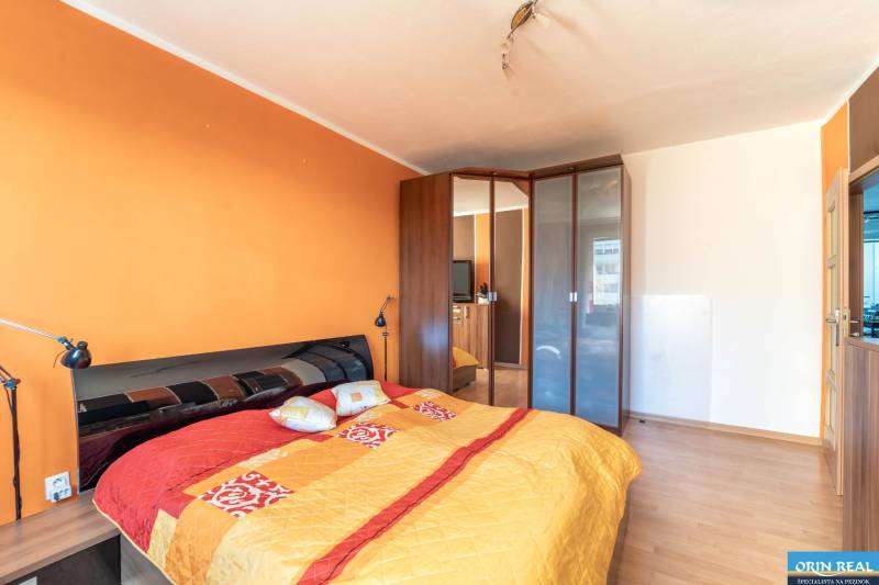 A bedroom with a large bed, a built-in wardrobe, and a wooden decor floor in a 3-room apartment.