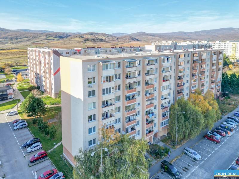 Apartment building on Svätoplukova Street in Pezinok, with a parking lot and nature in the background.