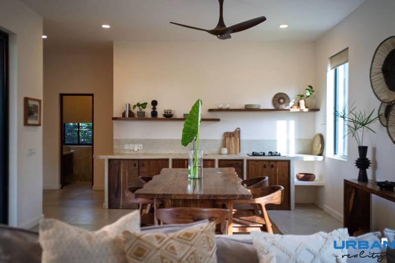 Interior of a kitchen with a wooden dining table, chairs, and shelves in the area of Home Construction.
