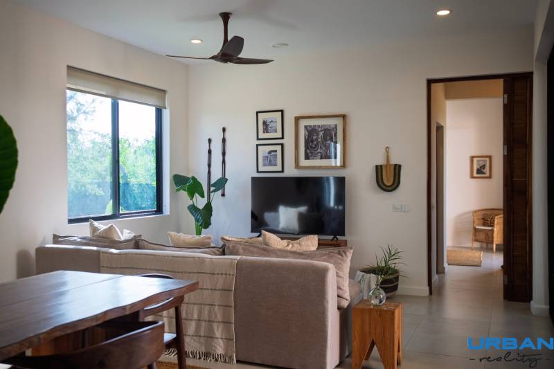 Interior with a sofa, television, and wooden furniture under construction of houses.