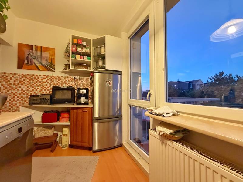 A kitchen in a 3-room apartment with a wooden decor floor and mosaic tiles.