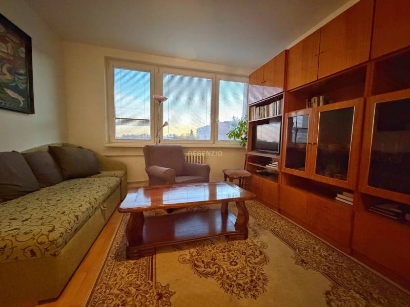 Living room with a sofa, armchair, wooden furniture, and a floor with a wooden decor in a 3-room apartment.