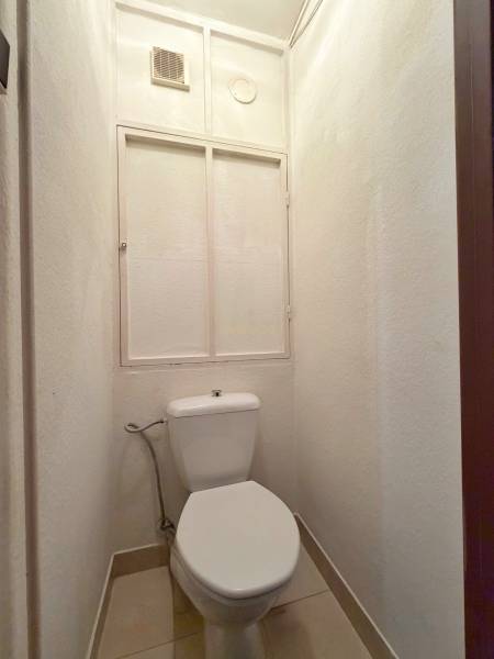 A toilet in a 3-room apartment with a simple design and white walls.