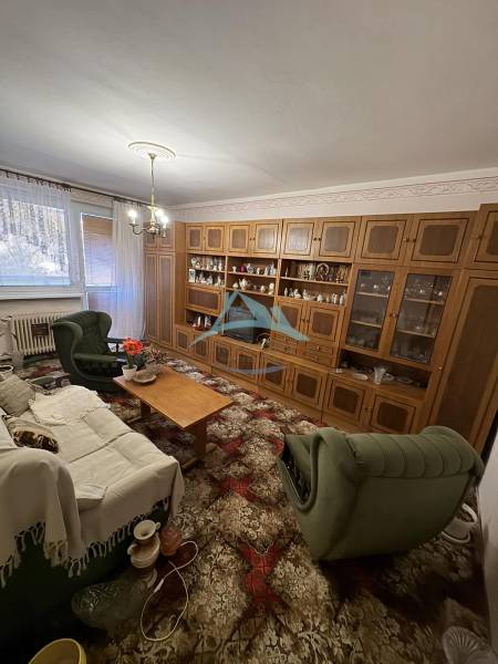 Living room in a 3-room apartment with a wooden wall unit and green furniture.