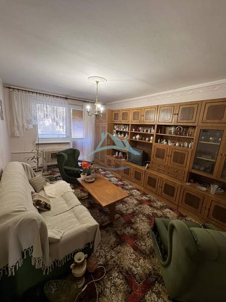 Living room in a 3-room apartment with a wooden wall unit and comfortable seating.