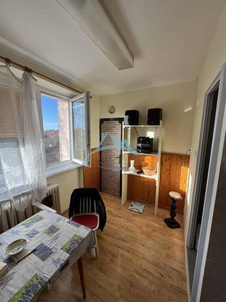 Dining room in a 3-room apartment with a wood-patterned floor and an open window.