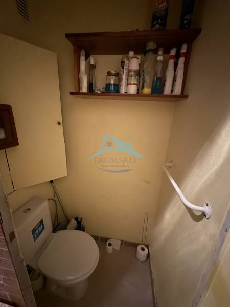 Bathroom with a toilet and a shelf for cleaning products in a 3-room apartment.