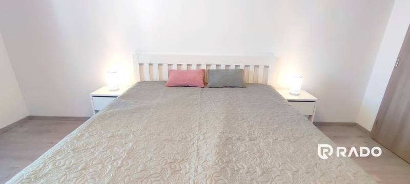 A bedroom with a bed, two pillows, and nightstands in a two-room apartment.