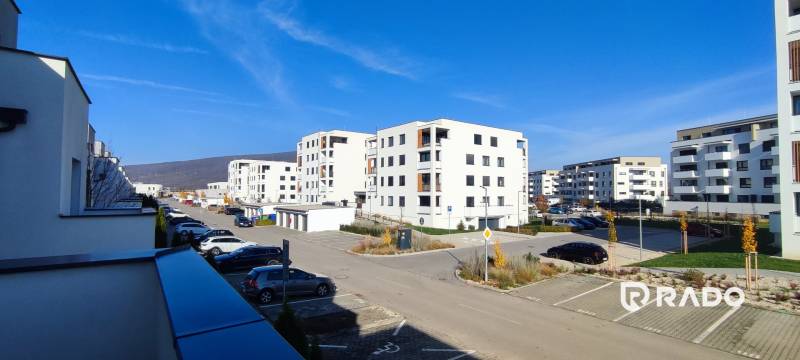 A set of white apartment buildings on Predmerského Street in Trenčín with parking spaces.
