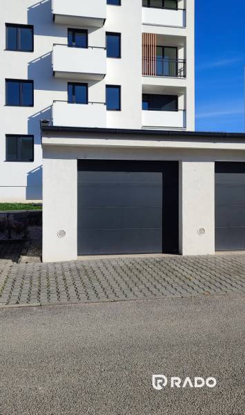 Garages on Predmerského Street in Trenčín with an apartment building in the background.
