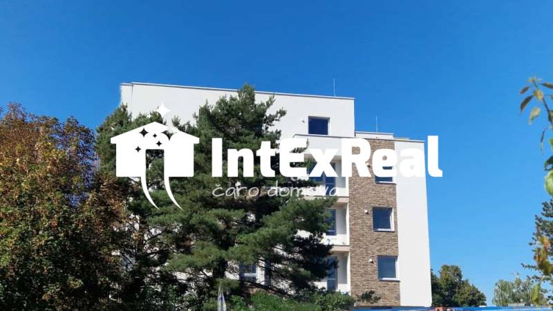 The building on Športová Street in Galanta, surrounded by trees, with a clear sky in the background.