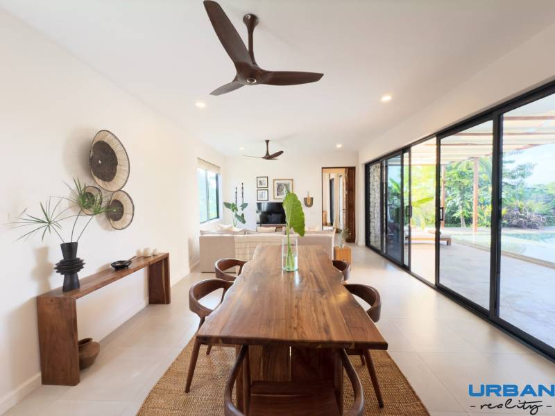 Dining room in a family house with a wooden table and a view of the yard through glass doors.