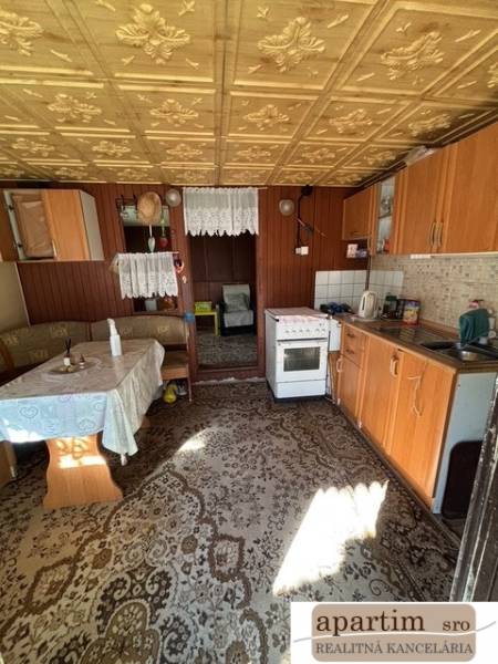 A kitchen with older furniture, a wooden decor floor, visible dining area.
