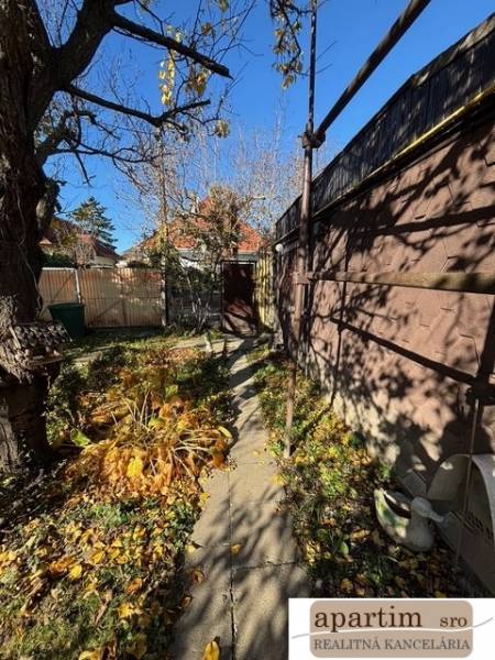 A narrow garden in Bratislava - Ružinov on Stredná Street with a walkway and trees.