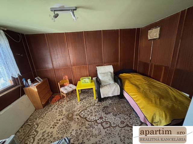 A room with chairs, a bed, a cabinet, and a decorative carpet in the Gardens.