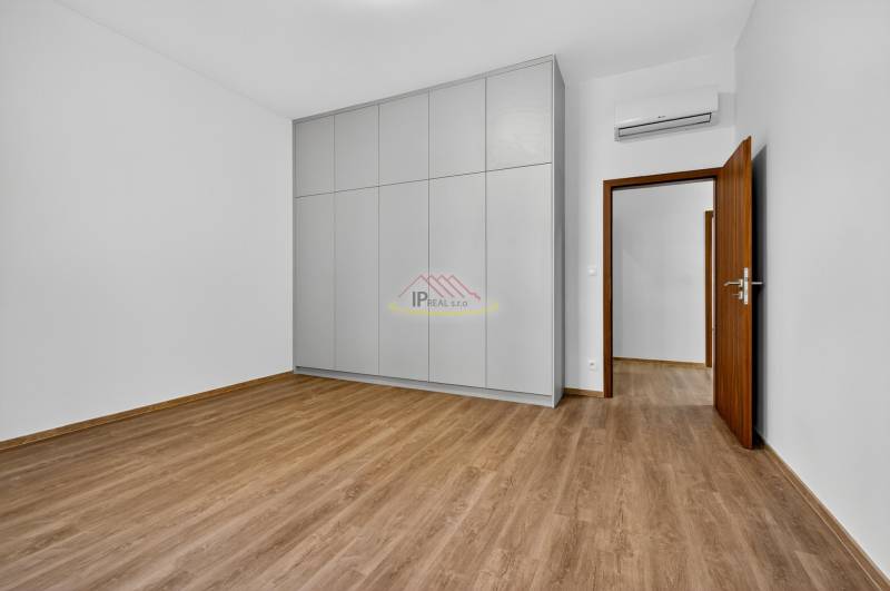 A room with a wooden decor floor, a built-in wardrobe, and white walls in a 4-room apartment.