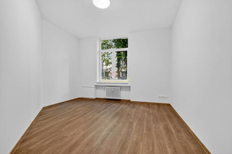 An empty room with light walls and a wooden decor floor in a 4-room apartment.