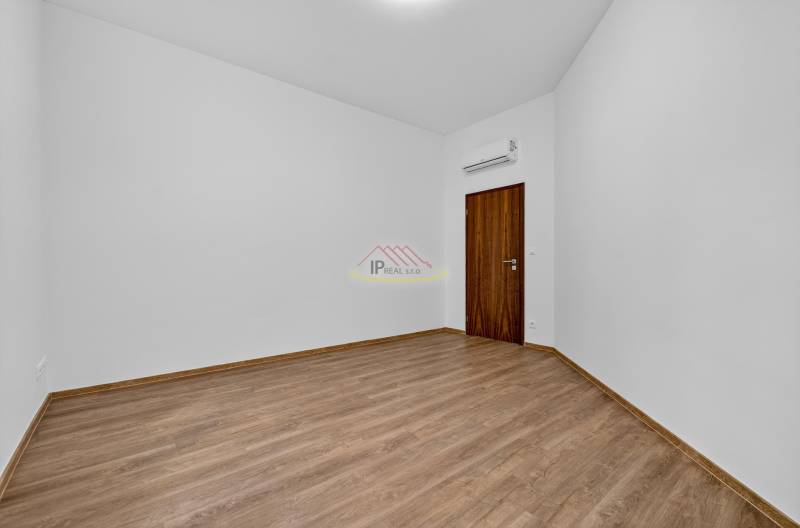 Empty space in a 4-room apartment with wood-patterned flooring and air conditioning.