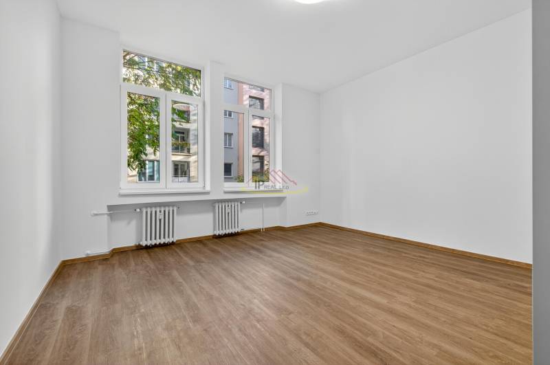 A bright room in a 4-room apartment with a wooden decor floor and large windows.