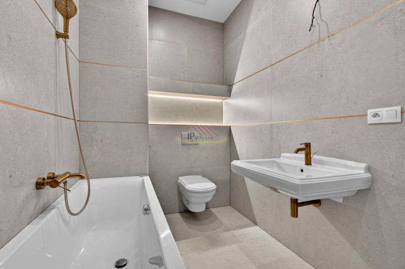 A bathroom with a bathtub, sink, gold faucets, and a toilet in a 4-room apartment.