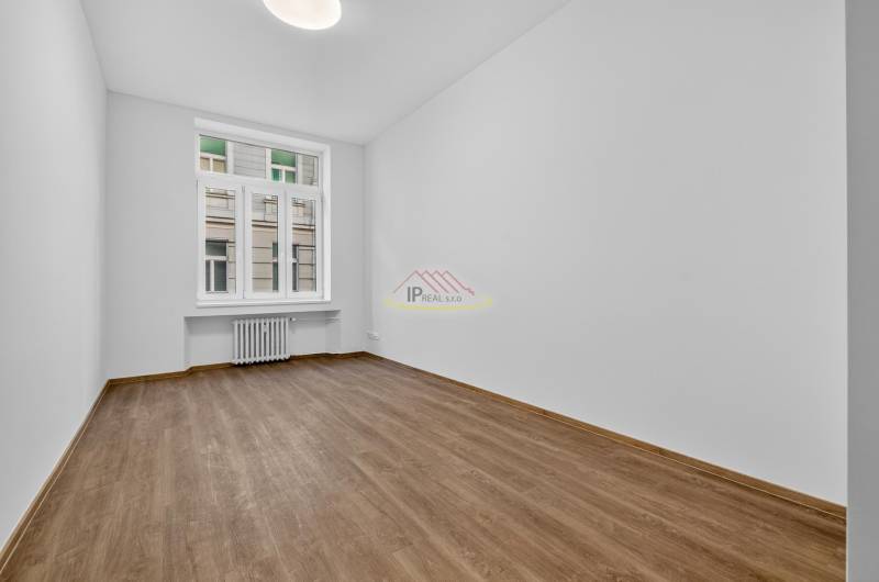 A room in a 4-room apartment with a wood-patterned floor and white walls.