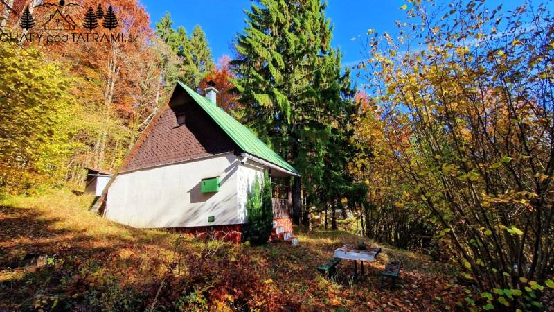 A cabin in Bystrá at Tále in the middle of an autumn forest, with a table and benches.