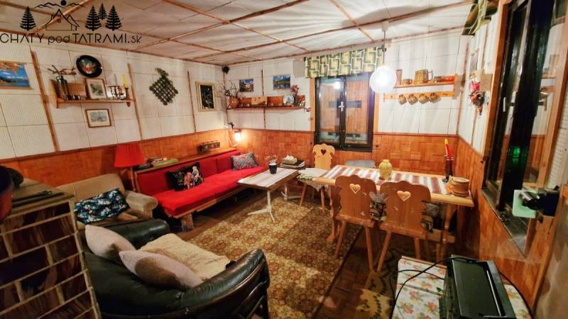 A cozy cabin interior with a decorated table, sofa, and wooden chairs.