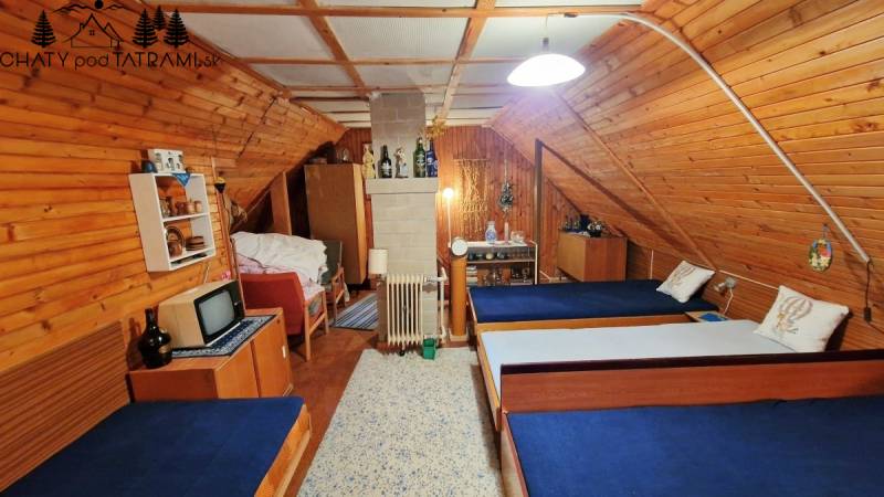 A wooden interior of a cabin with three beds and a television in a traditional style.