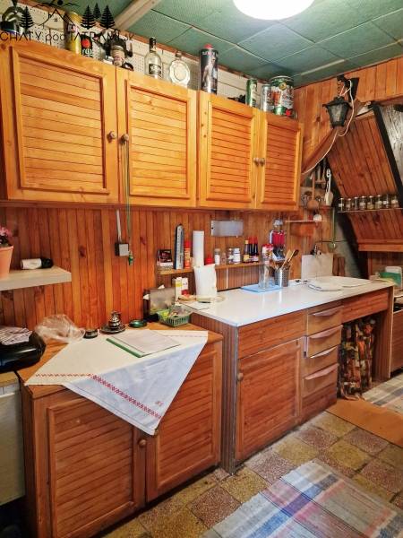 A kitchen in a cottage with wooden cabinets and a white countertop, cozy atmosphere.