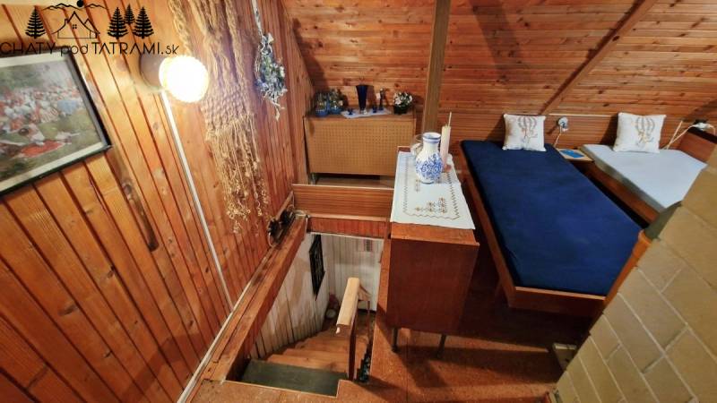 Wooden walls in a cabin with a bed, stairs, and decorative items on the table.