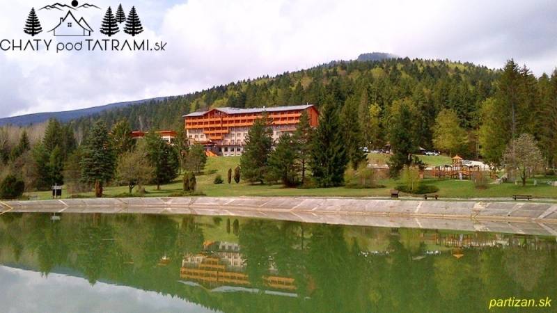 Mountain hotel surrounded by forests in Tále in Bystrá with a pond in the foreground.
