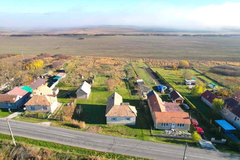 Houses by the main road in Radnovce, with plots - living surrounded by fields.