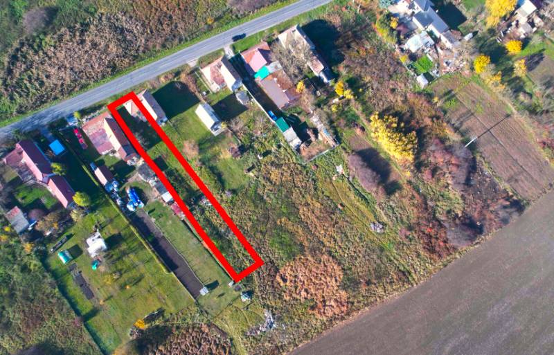 Aerial perspective of residential plots in the village of Radnovce with the main road.