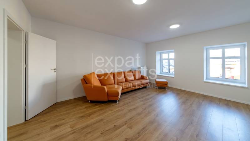 Living room with an orange sofa and a wooden decor floor in a two-room apartment.