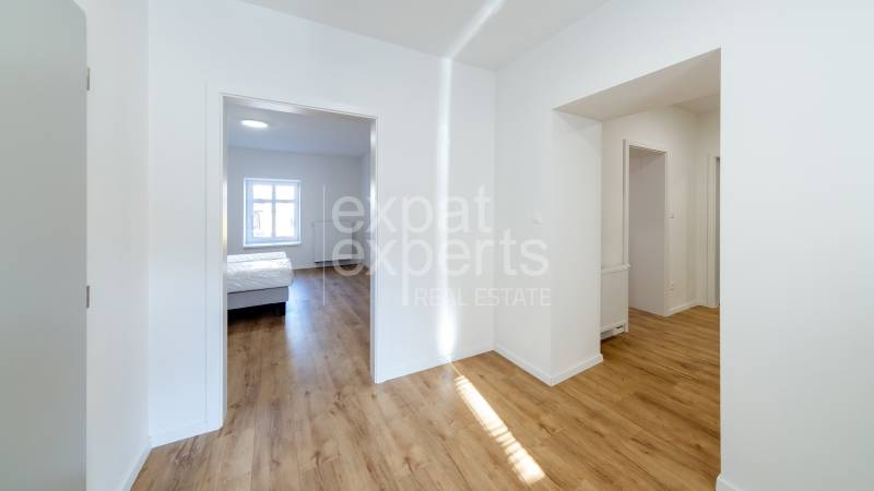 2-room apartment with wood-patterned flooring and a bedroom, bright interior.