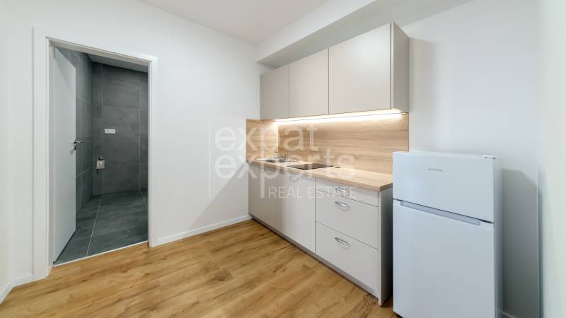 Kitchen corner with white cabinets, wooden decor, next to a refrigerator, in a 2-room apartment.