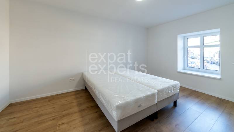 Bedroom in a 2-room apartment with a bed and a wooden decor floor.