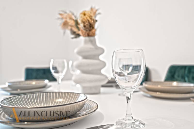 A table set with plates and glasses in a family home, a tasteful vase with flowers.