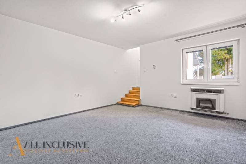Living room with carpeted floor, window, and stairs in a family house.