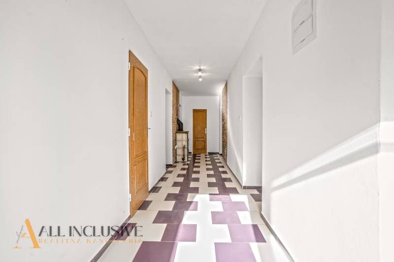 A hallway in a family house with a colorful geometric floor and wooden doors.