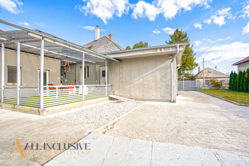Family house in Veľké Kosihy: concrete terrace, shelter, garden, blue sky.
