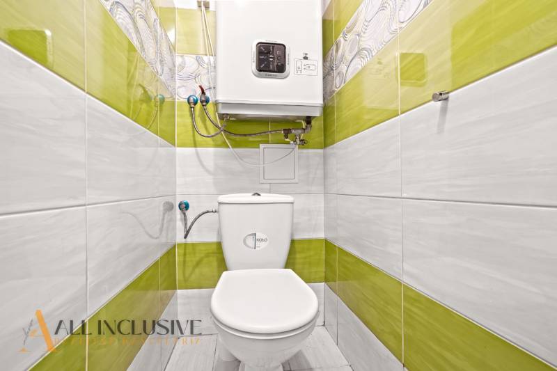 A family house bathroom with green tiles and a toilet.