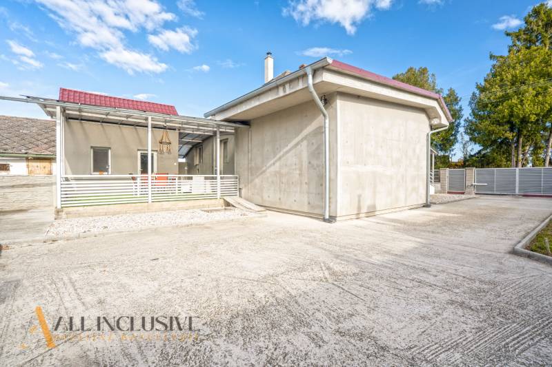 A family house in Veľké Kosihy with a terrace and a wide driveway, surrounded by greenery.