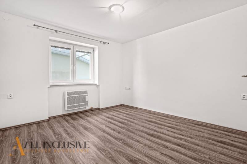 An empty room with white walls and a wood-patterned floor in a family house.
