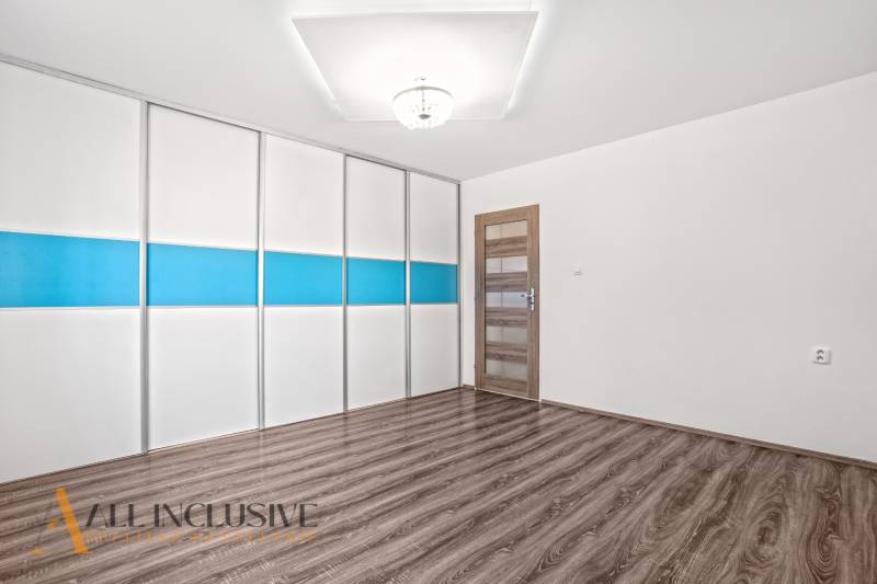 White room with a colorful built-in wardrobe and a wooden decor floor in a family house.