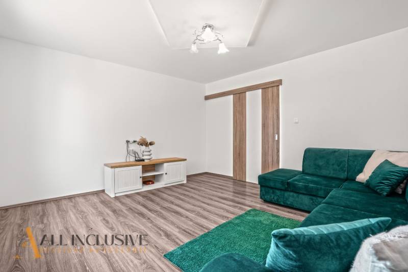 Interior of a family house with a wooden decor floor, green sofa, and table.